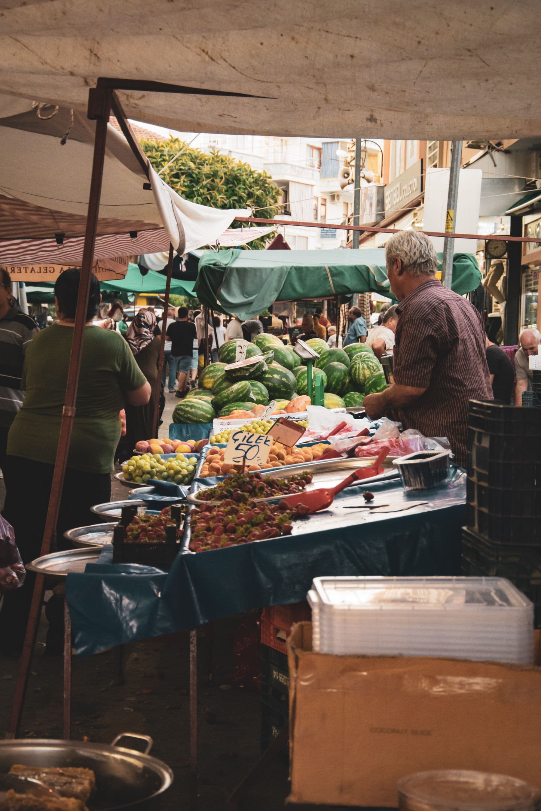 Two traders greeting each other across a busy market stall